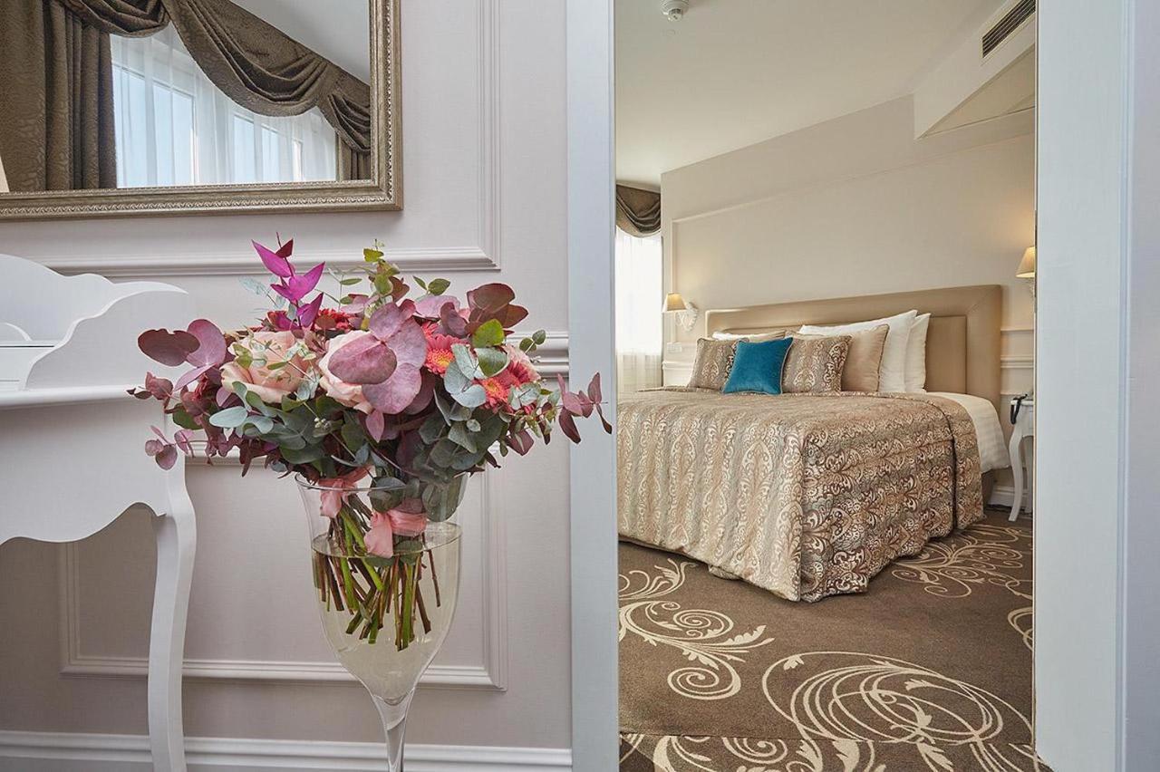 Don Giovanni Hotel Prague - Great Hotels Of The World Exterior photo The photo shows an inviting interior space that includes a well-decorated bedroom and a stylish floral arrangement. On the left side, there’s a tall vase containing colorful flowers, featuring shades of pink and green. The vase is situated on a white